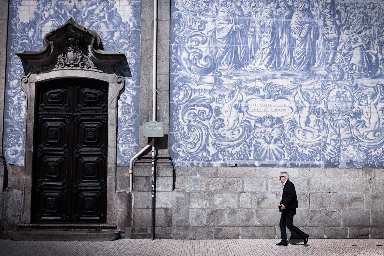 A man walks by a traditional azulejo wall in Porto, capturing the essence of Portuguese art and culture.