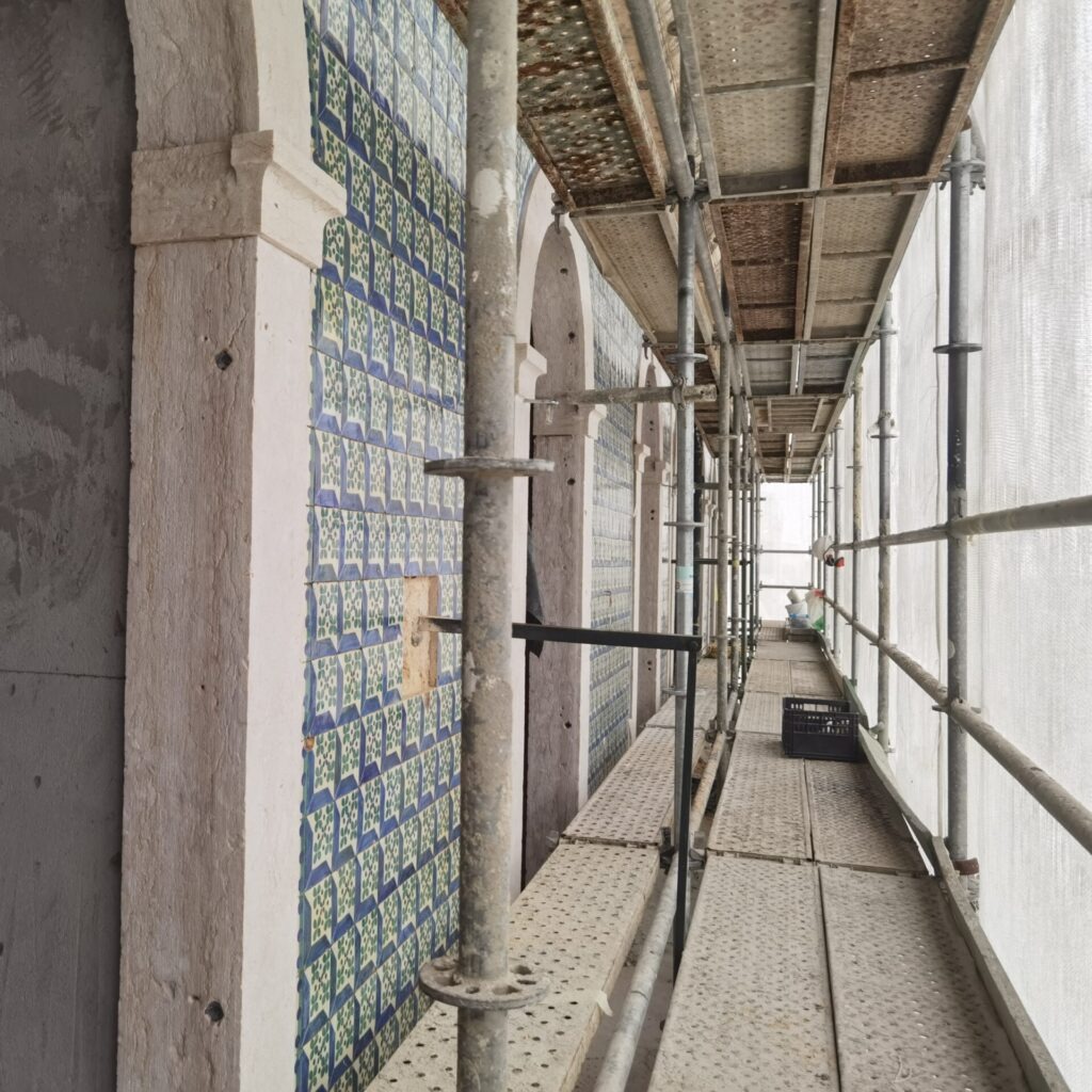 IMG_20240405_085607 Intervenção de restauro e conservação de azulejos em fachada exterior, com montagem de andaimes e trabalhos de estabilização estrutural. O processo inclui limpeza das superfícies, fixação de peças destacadas e reposição de azulejos em falta, garantindo a preservação estética e funcional do revestimento cerâmico histórico exposto às intempéries.